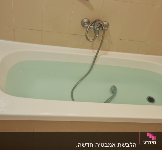 אמבטיה עם מים וברז מקלחת על הקיר